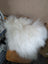 The moo cushion plush white fur throw with long wool draped over a wooden chair by angus oliver