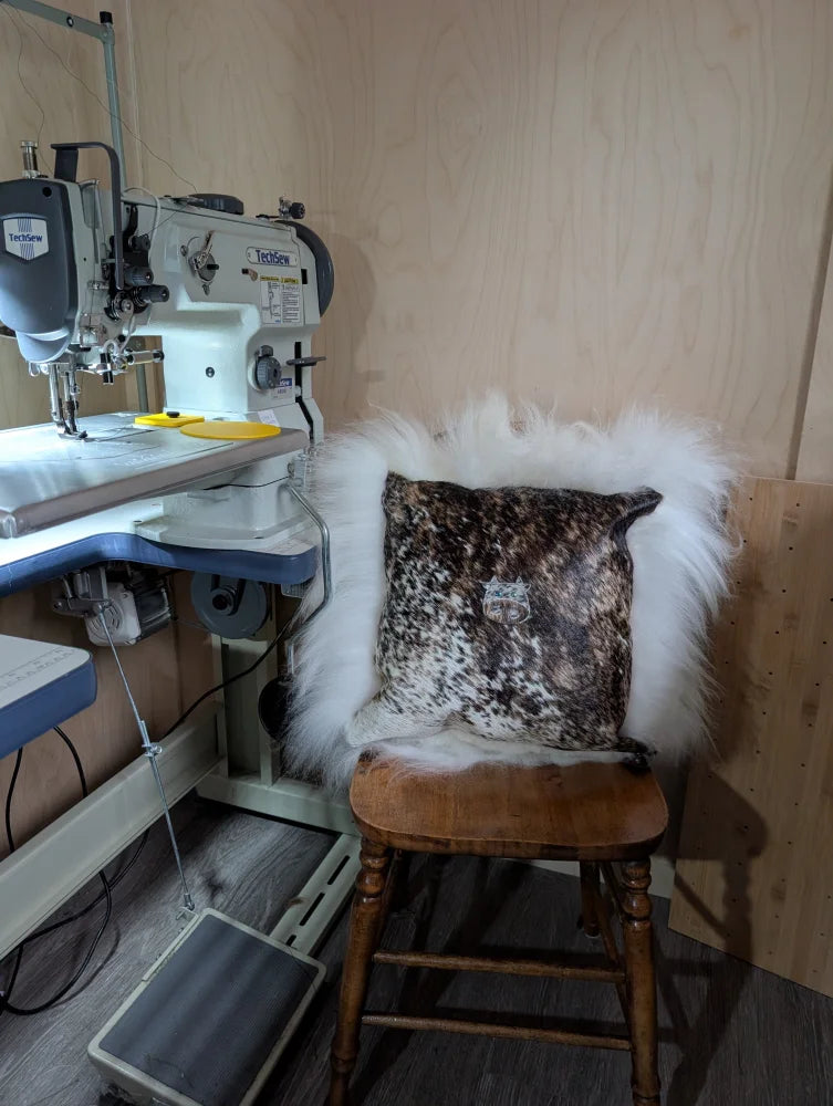 A rustic wooden chair with the moo cushion featuring a speckled angus oliver design and plush long wool throw
