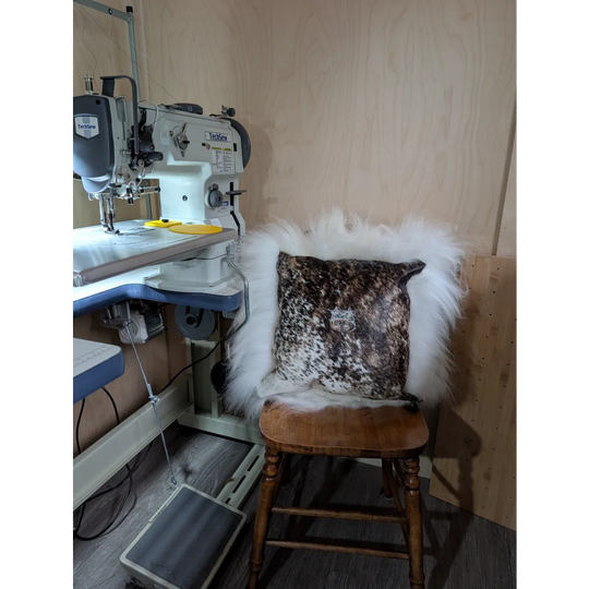 A rustic wooden chair with the moo cushion featuring a speckled angus oliver design and plush long wool throw