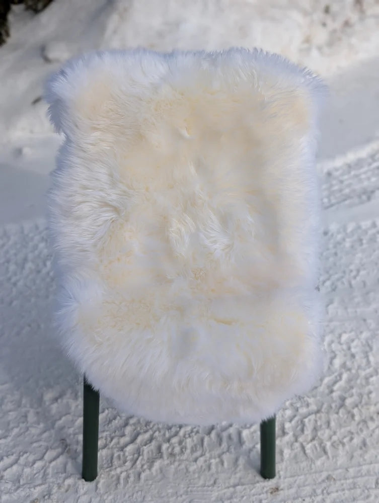 Gorgeous Merino sheepskin rug on green legs, OEKO-TEX certified, snowy backdrop