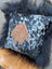 The yeti cushion cowhide pillow with black and white pattern features a brown hand-shaped leather patch and black long wool faux fur frame