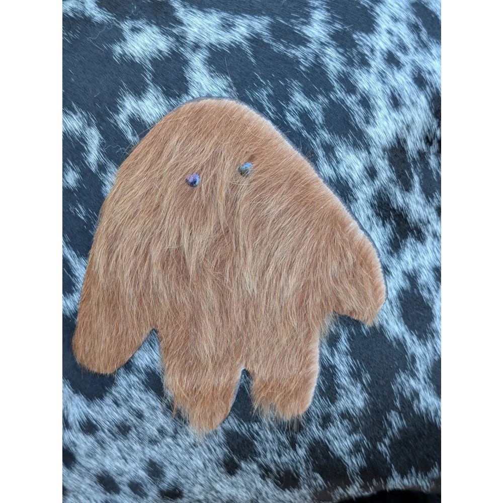 A plush tan fuzzy hand-shaped ornament with blue gem eyes made from icelandic sheepskin long wool for cozy decor
