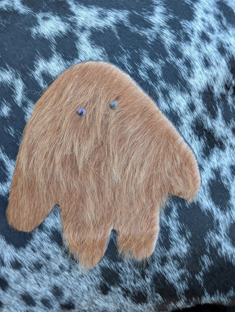 A plush tan fuzzy hand-shaped ornament with blue gem eyes made from icelandic sheepskin long wool for cozy decor