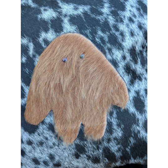 A plush tan fuzzy hand-shaped ornament with blue gem eyes made from icelandic sheepskin long wool for cozy decor