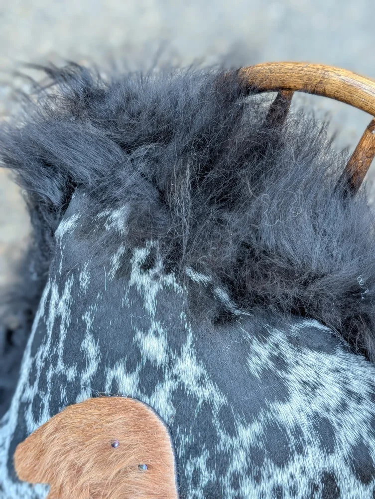 The yeti cushion cowhide bag features black and white spots with fluffy dark gray long wool icelandic sheepskin trim