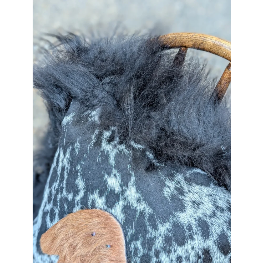 The yeti cushion cowhide bag features black and white spots with fluffy dark gray long wool icelandic sheepskin trim