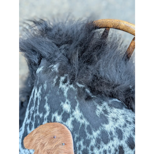 The yeti cushion cowhide bag features black and white spots with fluffy dark gray long wool icelandic sheepskin trim
