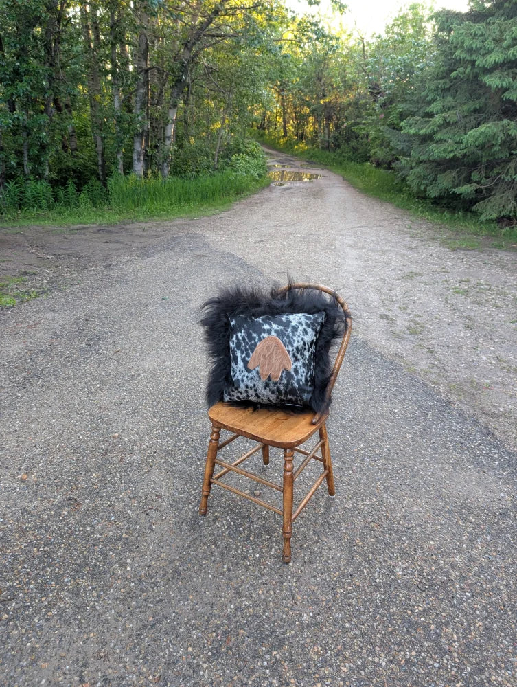 The yeti cushion icelandic sheepskin pillow with black and white cowhide paw print and fluffy black long wool trim