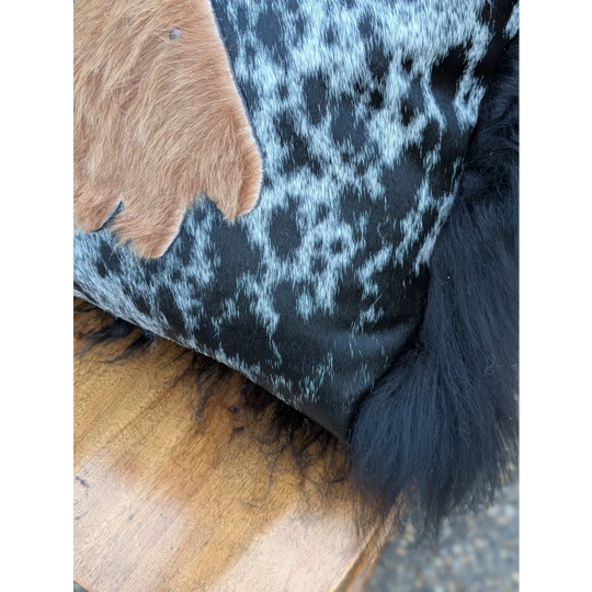 The yeti cushion cowhide pillow features black and white spots with a brown fur patch and black icelandic sheepskin trim