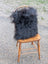 Black fluffy long wool icelandic sheepskin throw draped over wooden chair from the yeti cushion cowhide collection