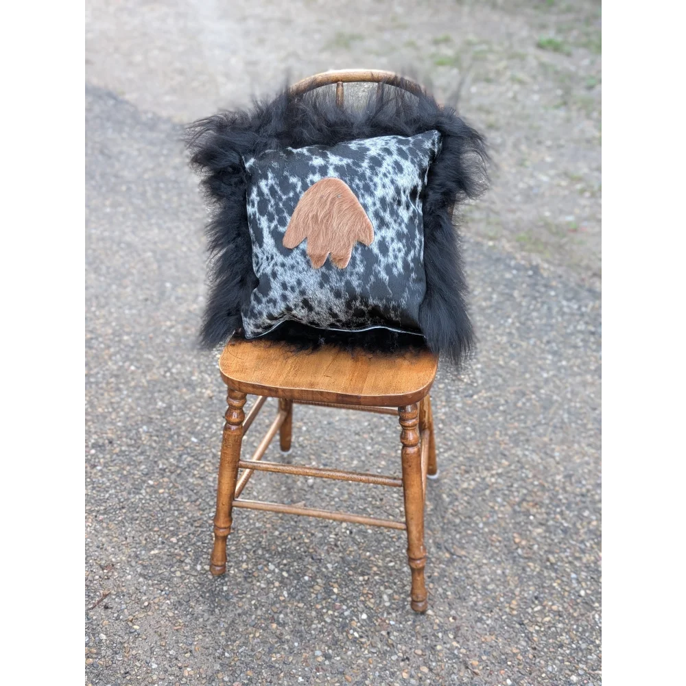 Black and white spotted pillow with tan hand patch framed by black long wool icelandic sheepskin from the yeti cushion
