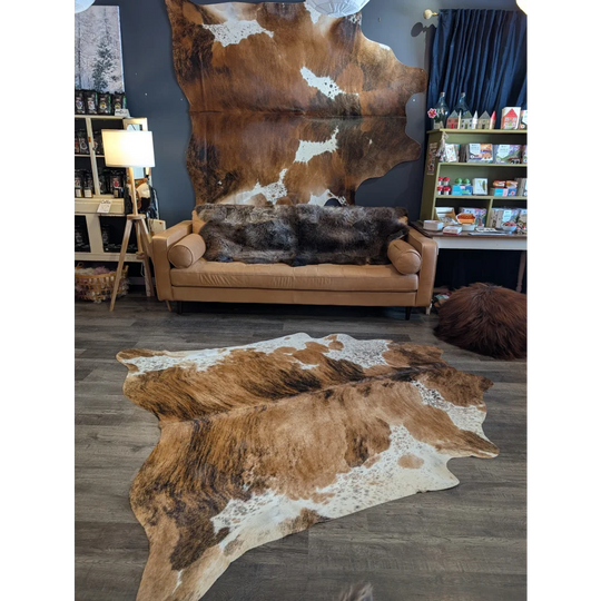 Brown and white extra large cowhide rug with natural patterns laid on wooden floor for beautiful rugs collection