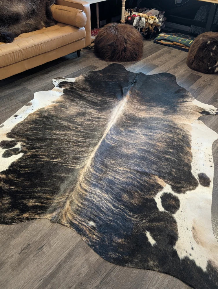 A beautiful large cowhide rug in natural black and white with a textured irregular pattern, extra large cowhide size