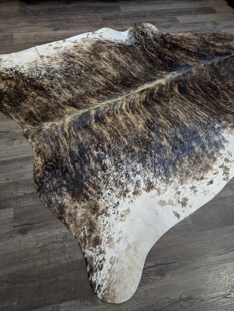 A beautiful extra large cowhide rug in natural brown and white with a textured speckled pattern perfect for large spaces