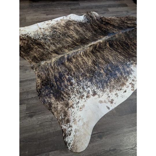 A beautiful extra large cowhide rug in natural brown and white with a textured speckled pattern perfect for large spaces