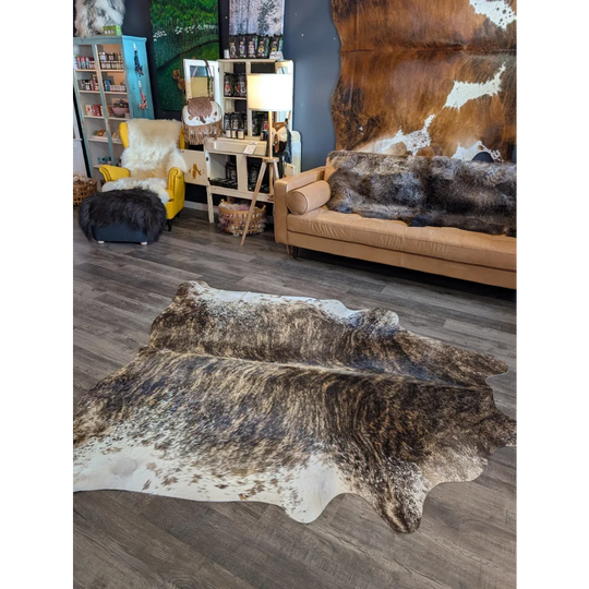 A beautiful extra large brown and white natural cowhide rug with a textured irregular pattern perfect for floors