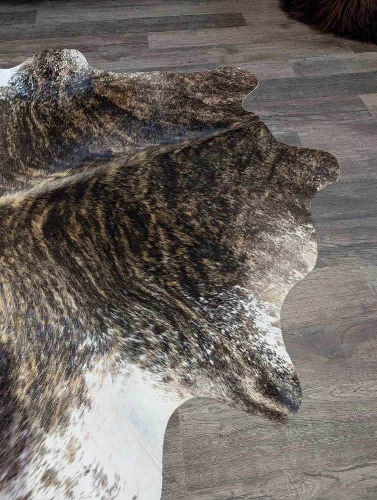 A beautiful extra large brown and white natural cowhide rug with textured irregular edges perfect for large spaces