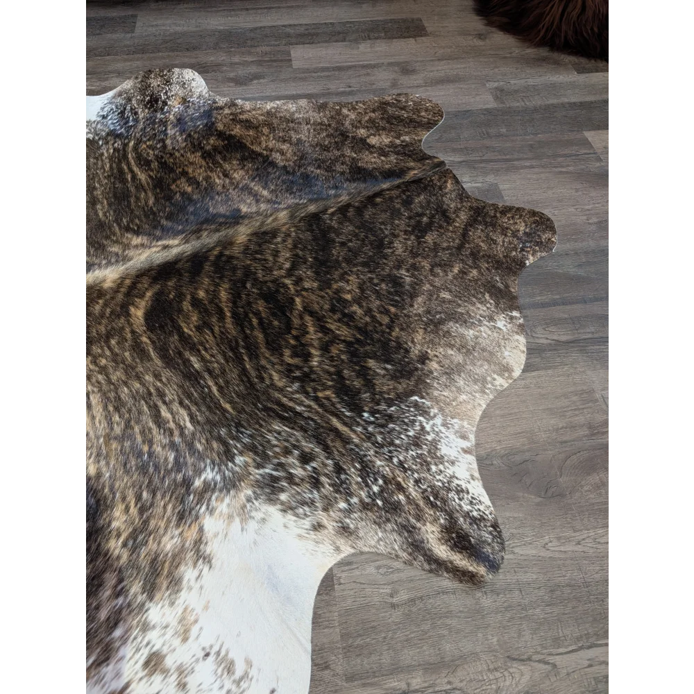 A beautiful extra large brown and white natural cowhide rug with textured irregular edges perfect for large spaces