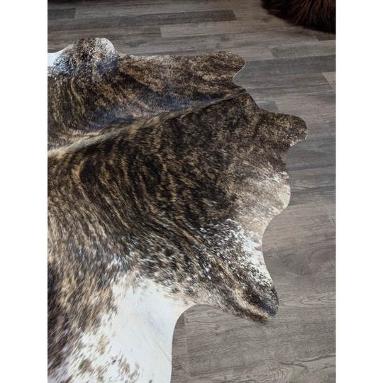 A beautiful extra large brown and white natural cowhide rug with textured irregular edges perfect for large spaces