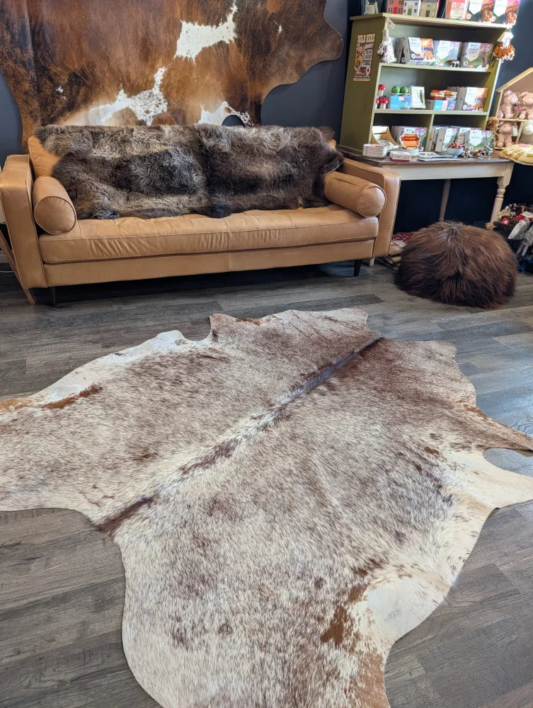Extra large natural-toned large cowhide rug with beautiful brown white and beige patches laid flat on floor
