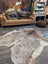Extra large natural-toned large cowhide rug with beautiful brown white and beige patches laid flat on floor