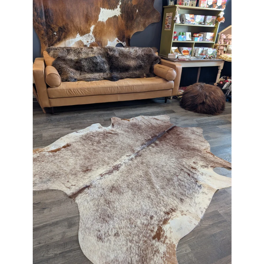 Extra large natural-toned large cowhide rug with beautiful brown white and beige patches laid flat on floor