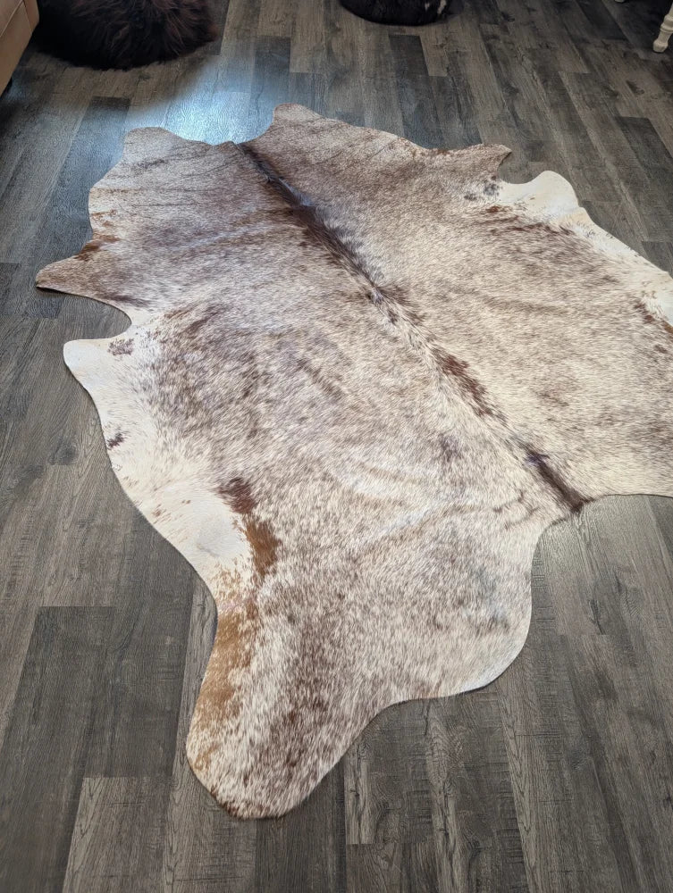 Extra large natural-toned large cowhide rug with mottled beige brown and white fur perfect for beautiful rugs collection
