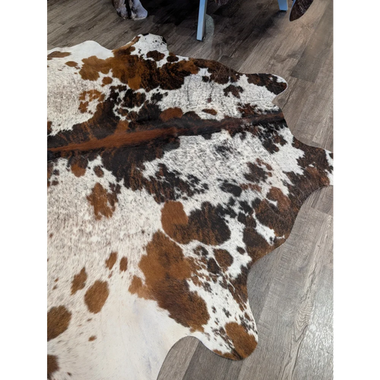 Extra large cowhide rug tricolour101 with brown white and black patches showcasing rustic charm and unique characteristics
