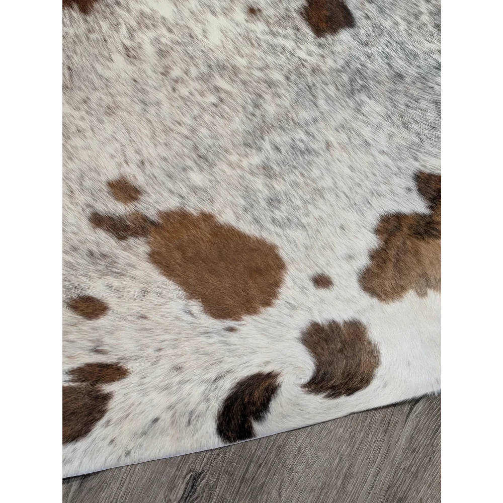A white and brown extra large cowhide rug with rustic charm and unique characteristics in a natural fluffy texture