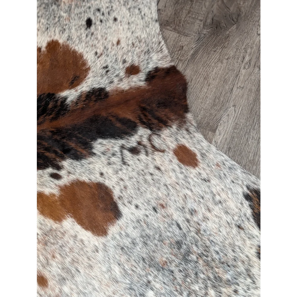 Extra large cowhide rug with brown and black spots and natural textured surface adds rustic charm and unique characteristics