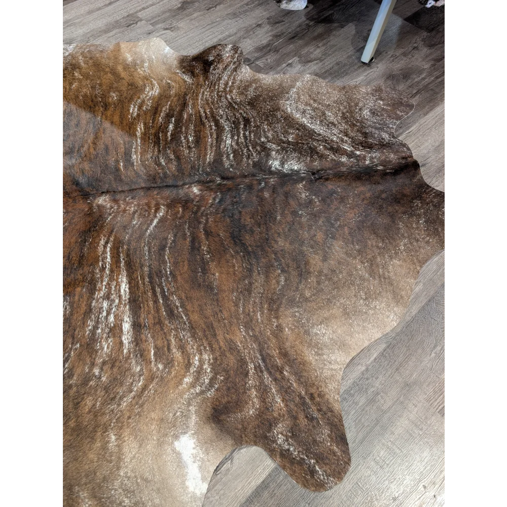 Brown and white extra large cowhide rug with rustic charm and unique characteristics featuring natural irregular edges
