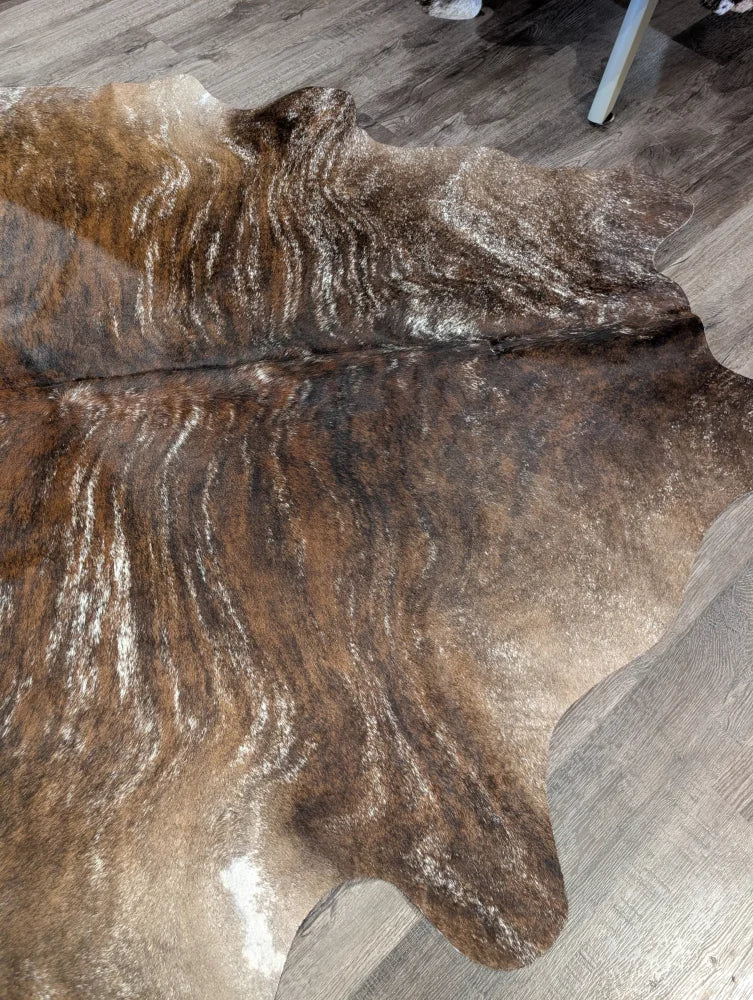 Brown and white extra large cowhide rug with rustic charm and unique characteristics featuring natural irregular edges
