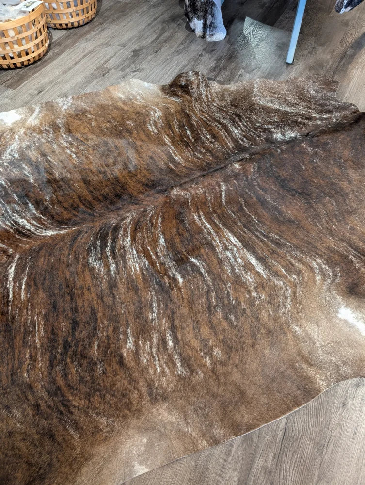 Brown and white extra large cowhide rug with natural textured fur pattern and unique characteristics for rustic charm