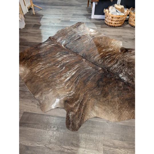 Brown and white extra large cowhide rug with natural irregular edges showcasing rustic charm and unique characteristics