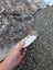 A hand holds a large cowhide rug with unique characteristics and rustic charm in white and dark brown patches