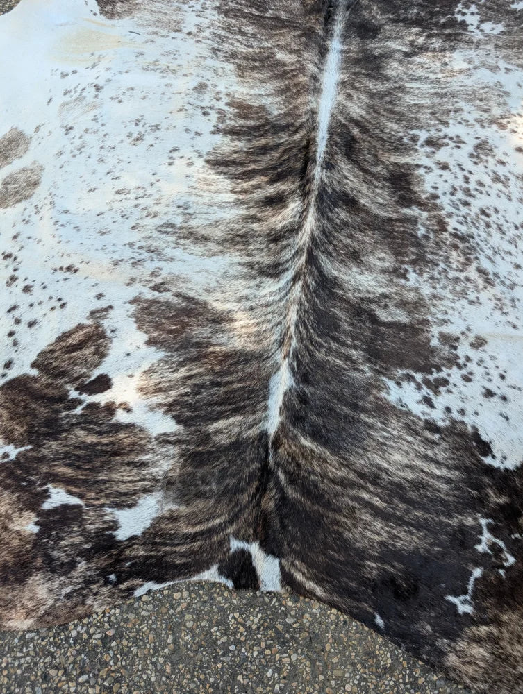 A large cowhide rug with black white and brown spotted pattern showcasing unique characteristics and rustic charm