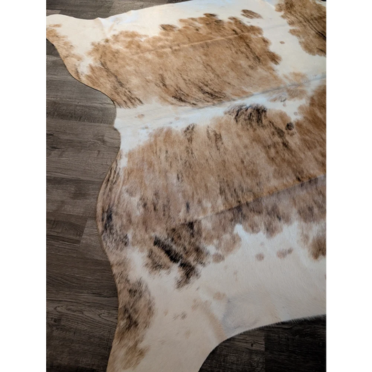 A gorgeous extra large cowhide rug in tri color white tan and brown spotted pattern perfect as a large cowhide decor