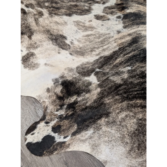 A gorgeous extra large cowhide rug with rustic charm featuring a unique black white and gray spotted pattern