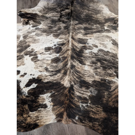 A gorgeous extra large cowhide rug with a tricolour black white and tan spotted pattern full of rustic charm and unique characteristics