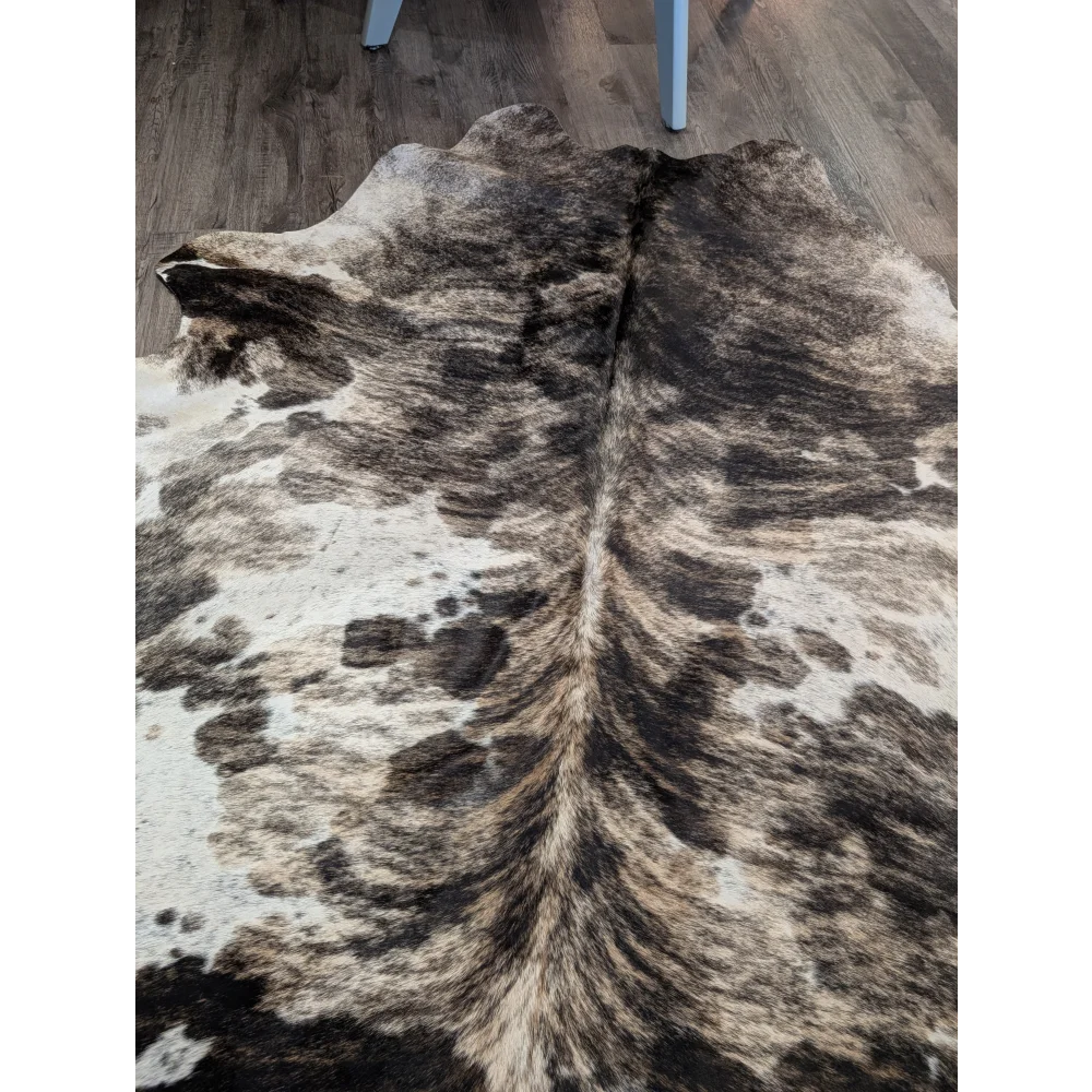 A gorgeous extra large cowhide rug with a tricolour black white and tan spotted pattern adding rustic charm and unique characteristics