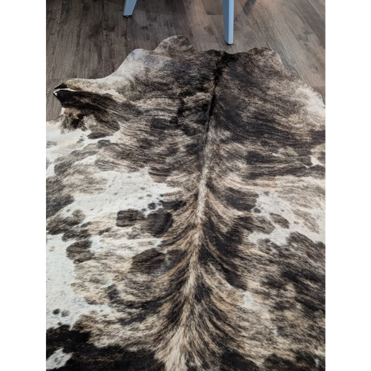 A gorgeous extra large cowhide rug with a tricolour black white and tan spotted pattern adding rustic charm and unique characteristics