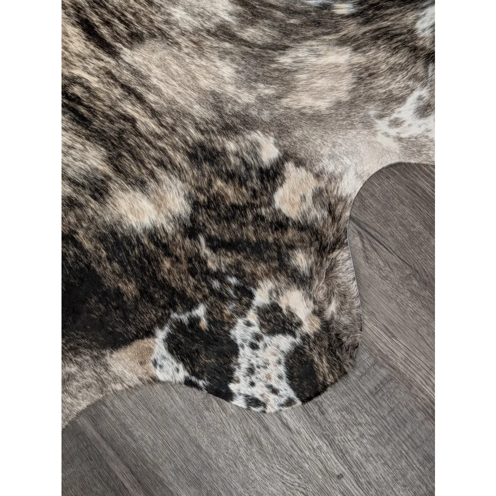 A plush extra large cowhide rug with rustic charm featuring a natural black white and tan spotted pattern