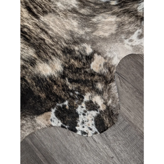 A plush extra large cowhide rug with rustic charm featuring a natural black white and tan spotted pattern