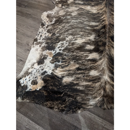 A gorgeous extra large cowhide rug with rustic charm featuring unique black white and tan mottled patches
