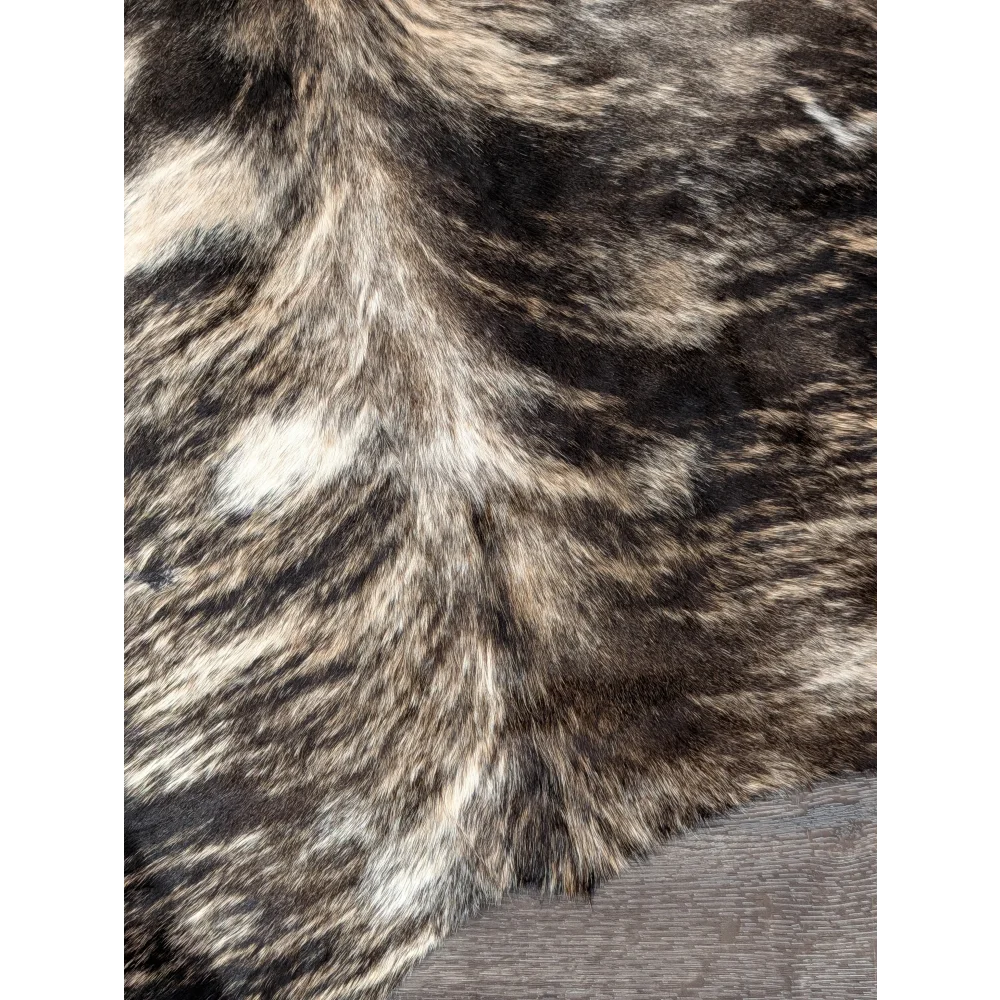A plush extra large cowhide rug in mottled brown and black faux fur with unique characteristics and rustic charm