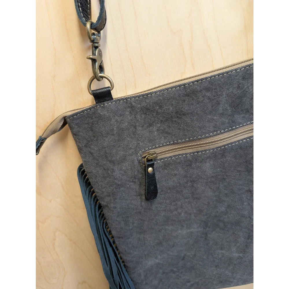 Gray denim crossbody bag tumbleweed 2 with black leather accents fringed detail and zippered pocket in smoky charcoal