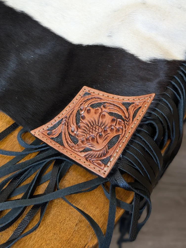 A tumbleweed #2 tassel purse with hand tooled tan leather patch and dark brown stitching on smoky charcoal fringe