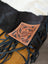 A tumbleweed #2 tassel purse with hand tooled tan leather patch and dark brown stitching on smoky charcoal fringe