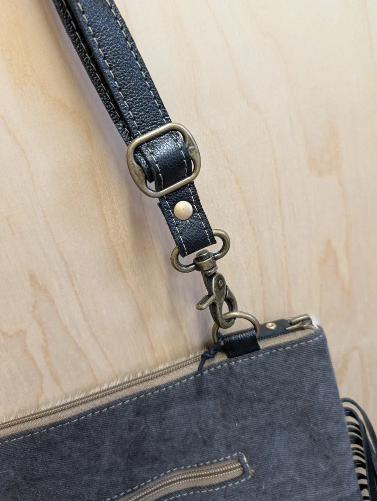 Dark blue denim tumbleweed 2 crossbody bag with smoky charcoal hand tooled leather strap and zippered pocket