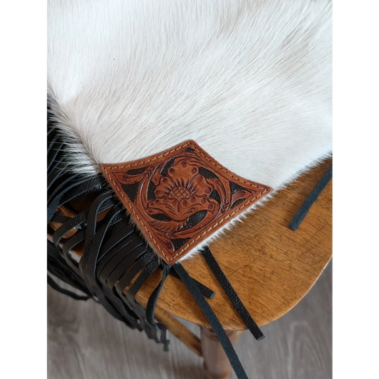 A tan hand tooled leather patch with black stitching on white cowhide for the tumbleweed 4 smoky charcoal tassel purse